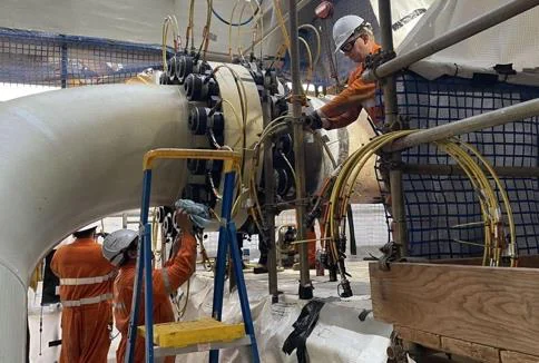 Crew applying composite wrap to a pipe